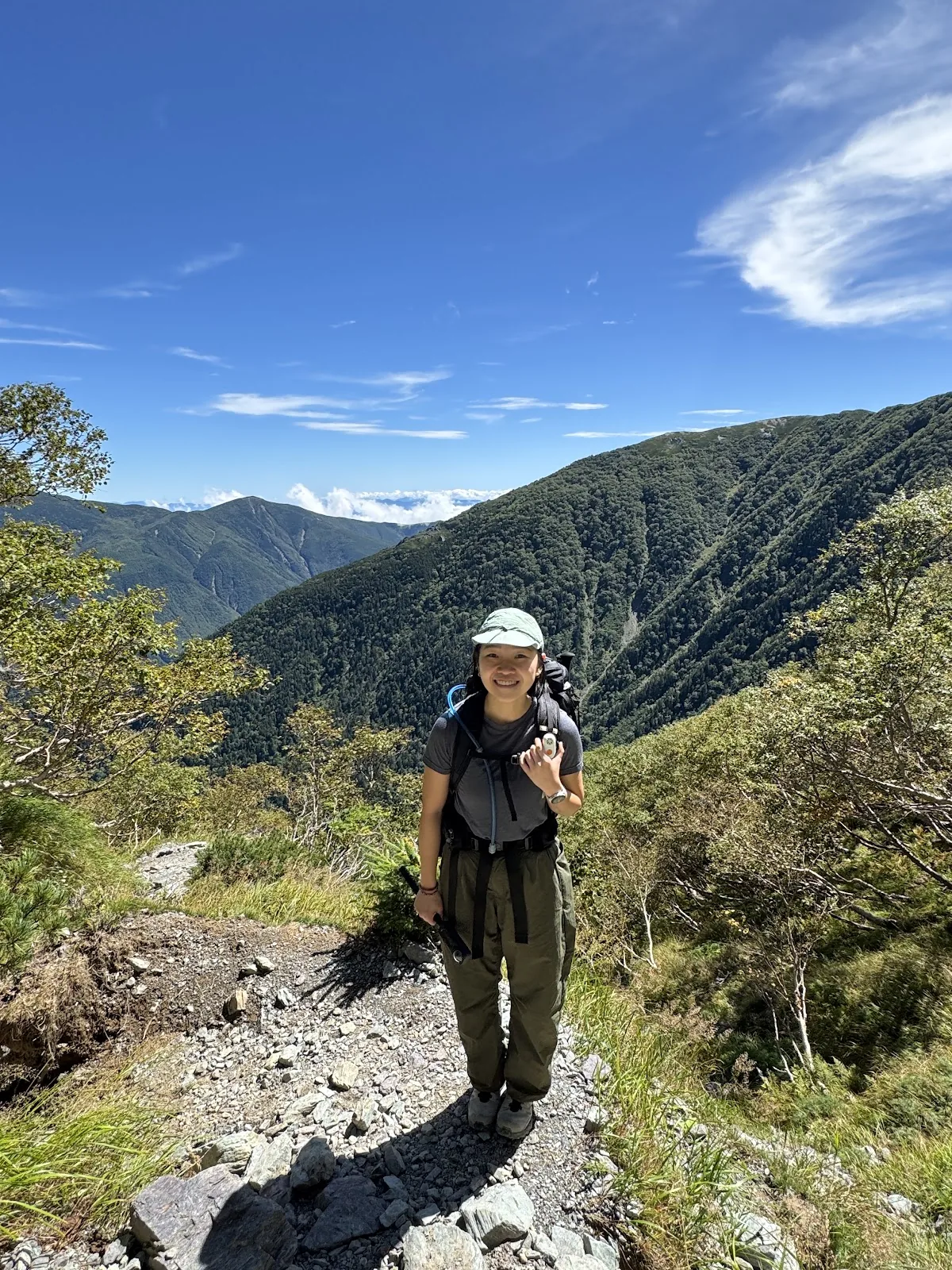 Hiker standing on an alpine trail under a bright blue sky