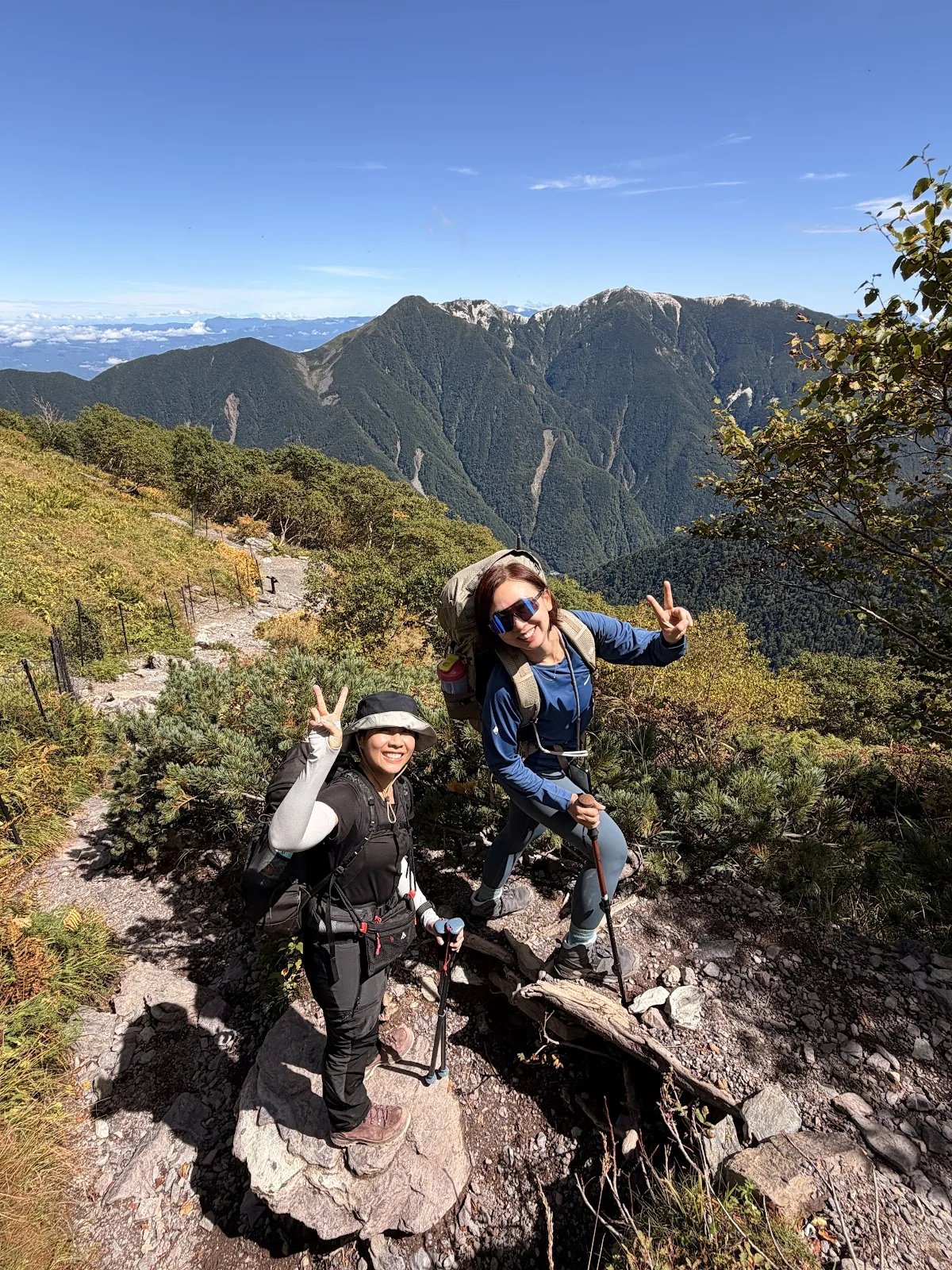 Two hikers smiling together on a high mountain ridge