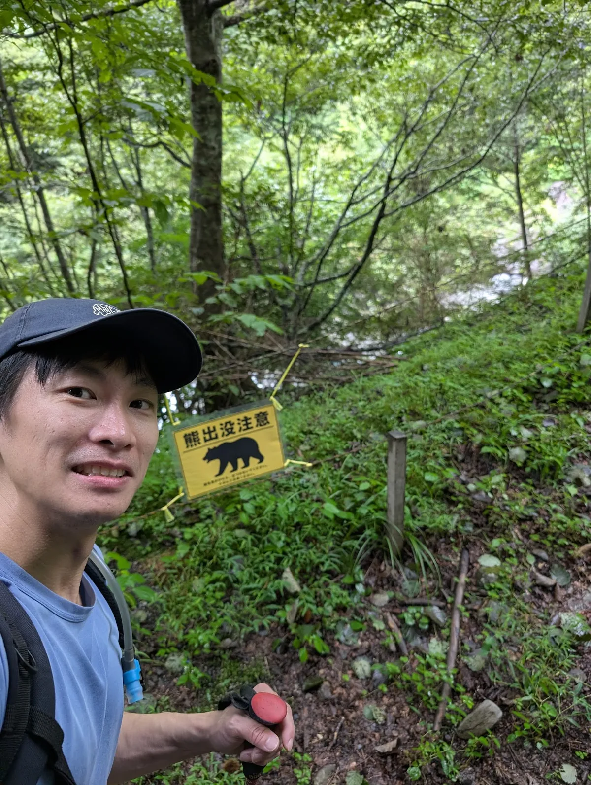 Hiker beside a bear warning sign at the trailhead