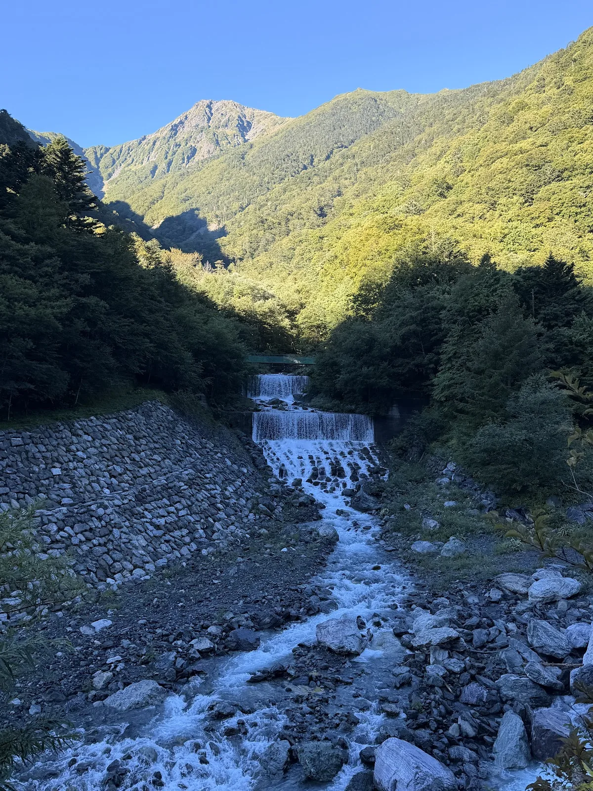 Waterfall and mountain valley under clear blue sky